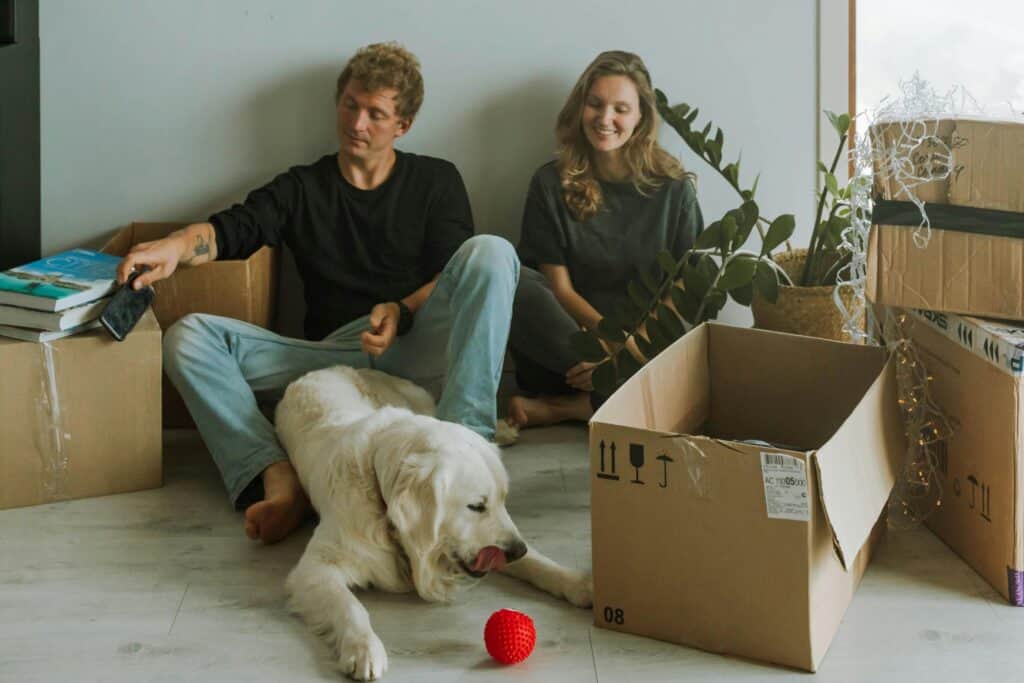 A couple with their pet dog surrounded by carton in the concept of moving to Wandsworth