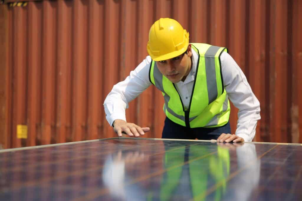 A male worker with a solar panel in front of him