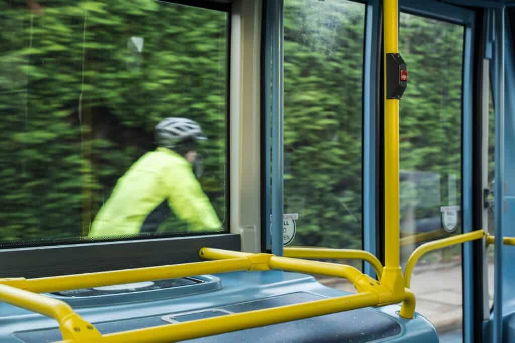 View from inside a bus and a cyclist outside on the same road